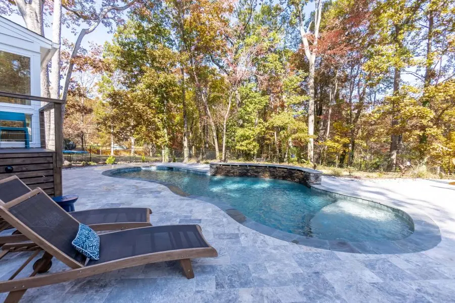 Inground pool with silver travertine and water feature wall