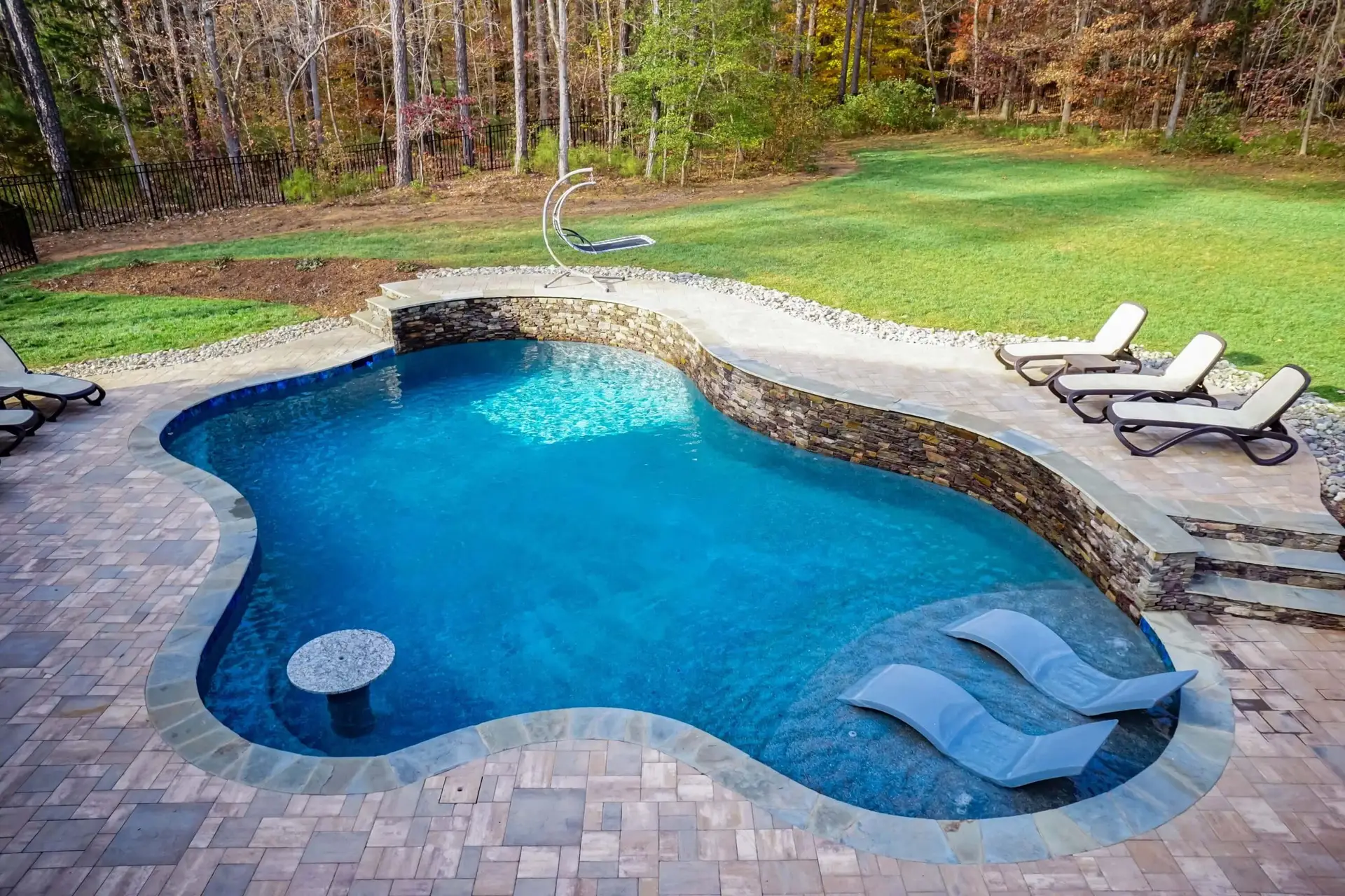 Custom Freeform pool in North Raleigh with pavers, stone work, tanning ledge and in pool seating - front right view