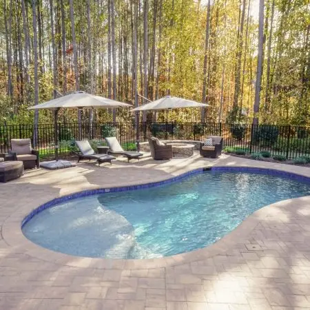 Youngsville NC custom concrete pool with Cambridge pavers, landscaping, fire pit, and seat wall