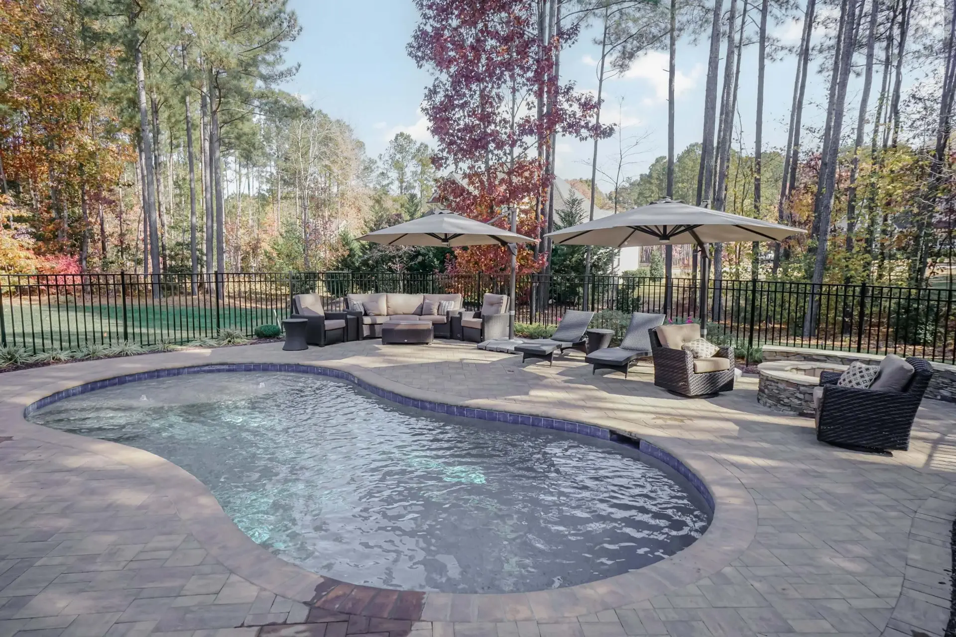 Youngsville NC custom concrete pool with Cambridge pavers, landscaping, fire pit, and seat wall - caddy corner view