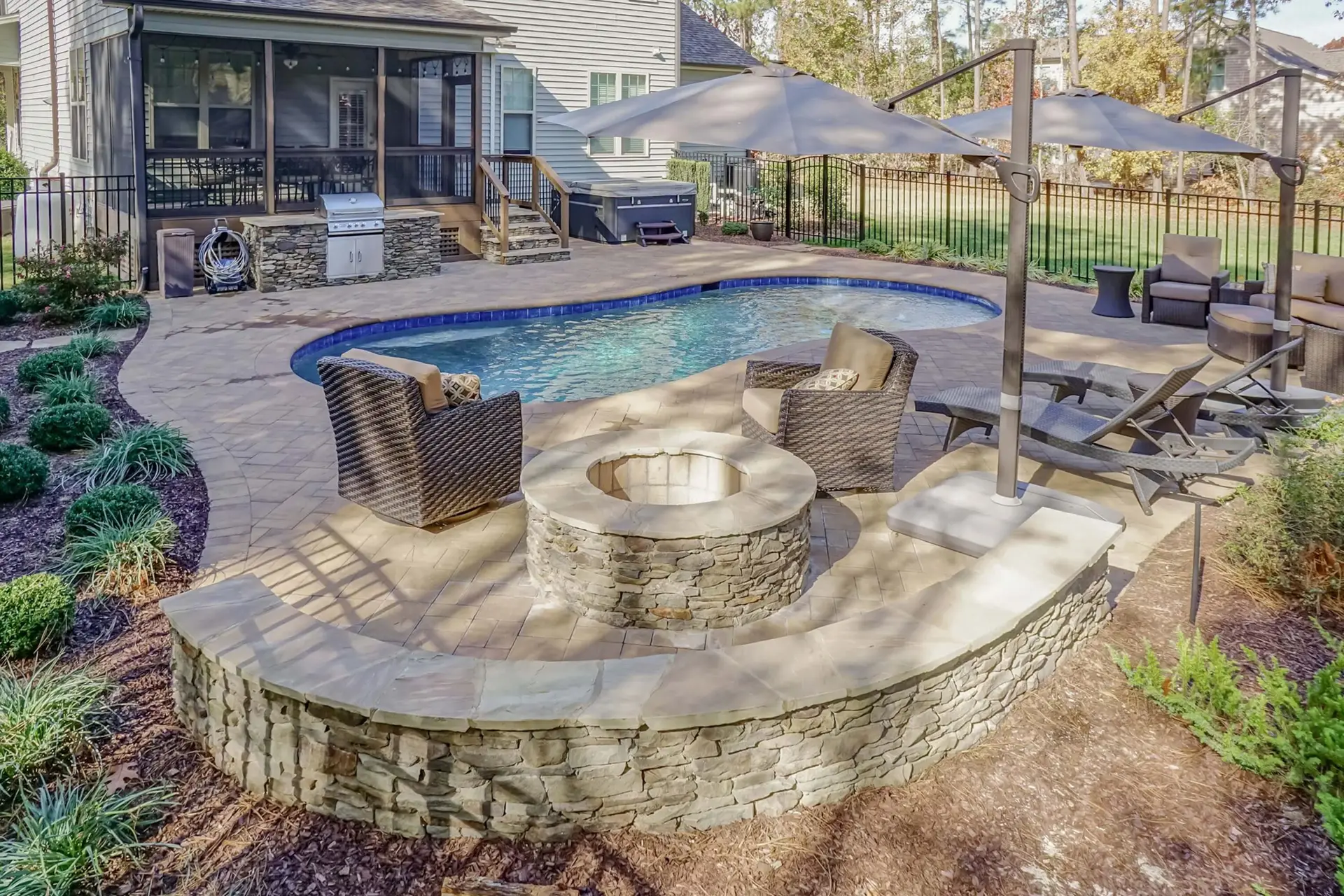 Youngsville NC custom concrete pool with Cambridge pavers, landscaping, fire pit, and seat wall - angle view 2