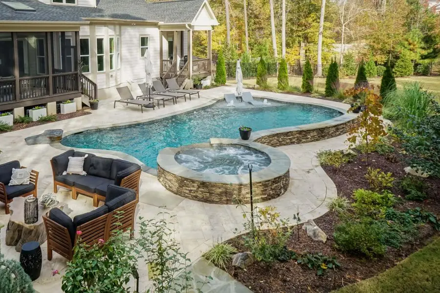 Custom pool in Wake Forest, NC with landscaping, spa, and travertine
