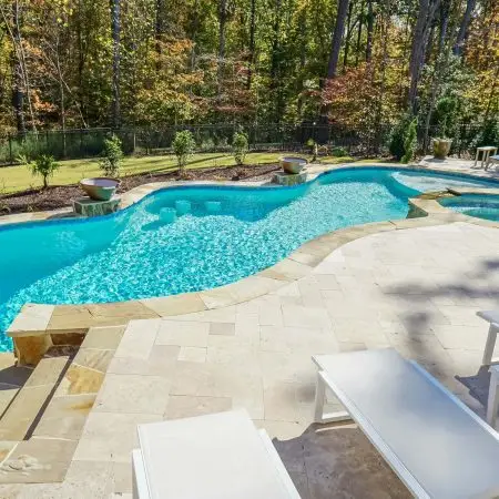 Luxury custom freeform pool with Pebbletec pool plaster and travertine in Wake Forest, NC