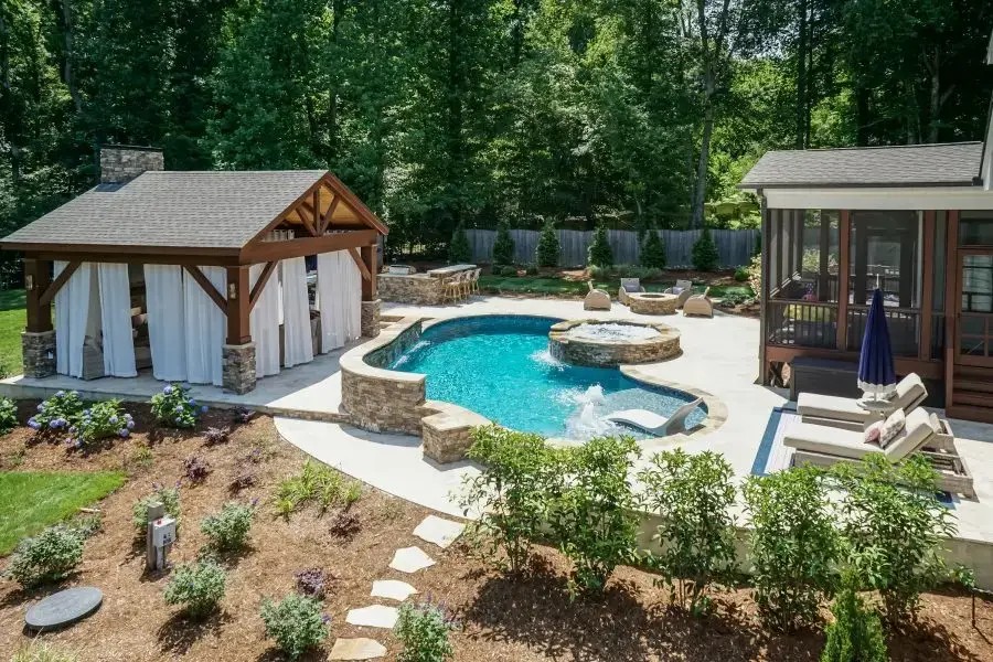 Complete backyard renovation with freeform pool, pavilion,grill island, fire pit, fireplace and landscape in Holly Springs, NC