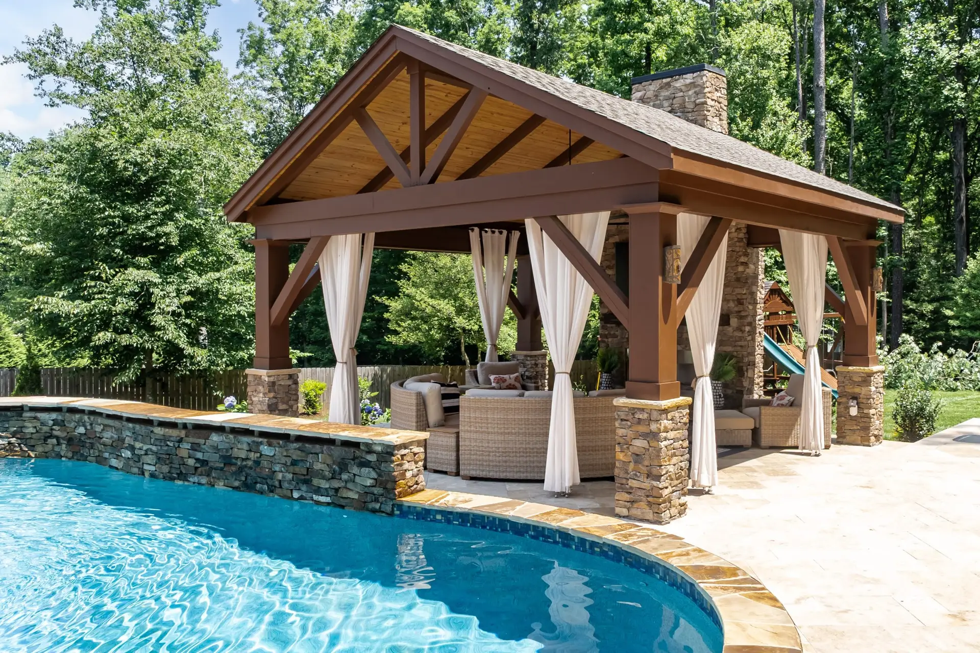 Custom pavilion and freeform pool in Holly Springs, NC backyard.